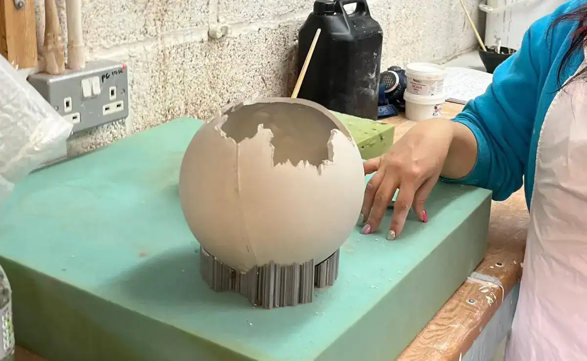 Ceramic globe lamp being crafted in workshop.