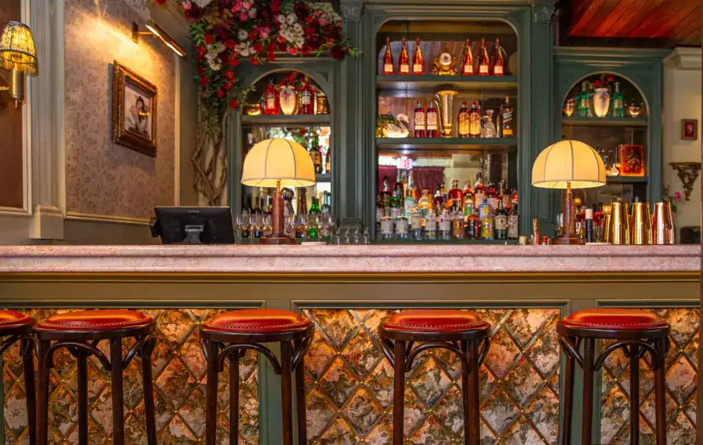 Elegant bar interior with vintage lighting and colourful bottles display.