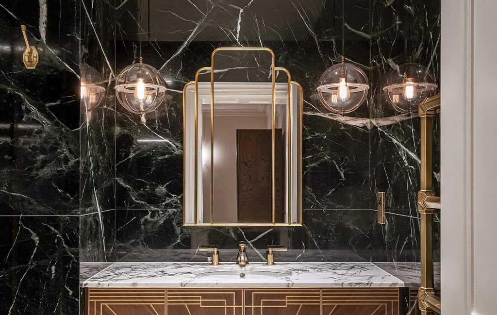 Elegant bathroom with black marble walls and gold lighting fixtures.