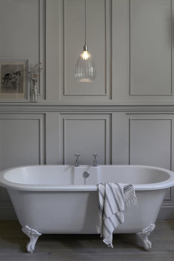 Elegant pendant light over classic bathtub in bathroom.
