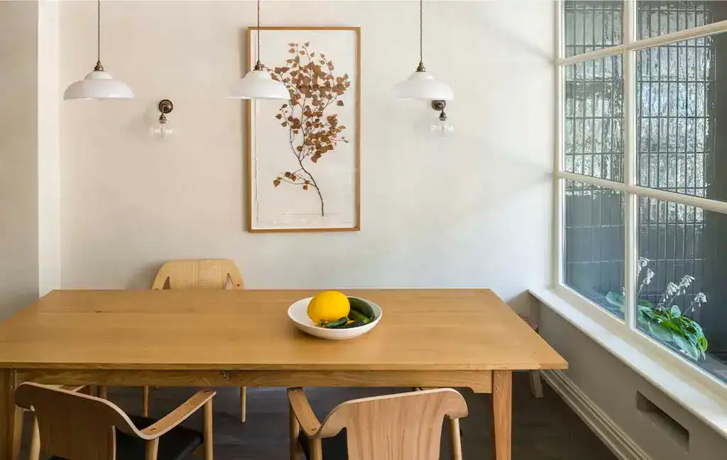 Pendant lighting over a wooden dining table in a bright, airy room.