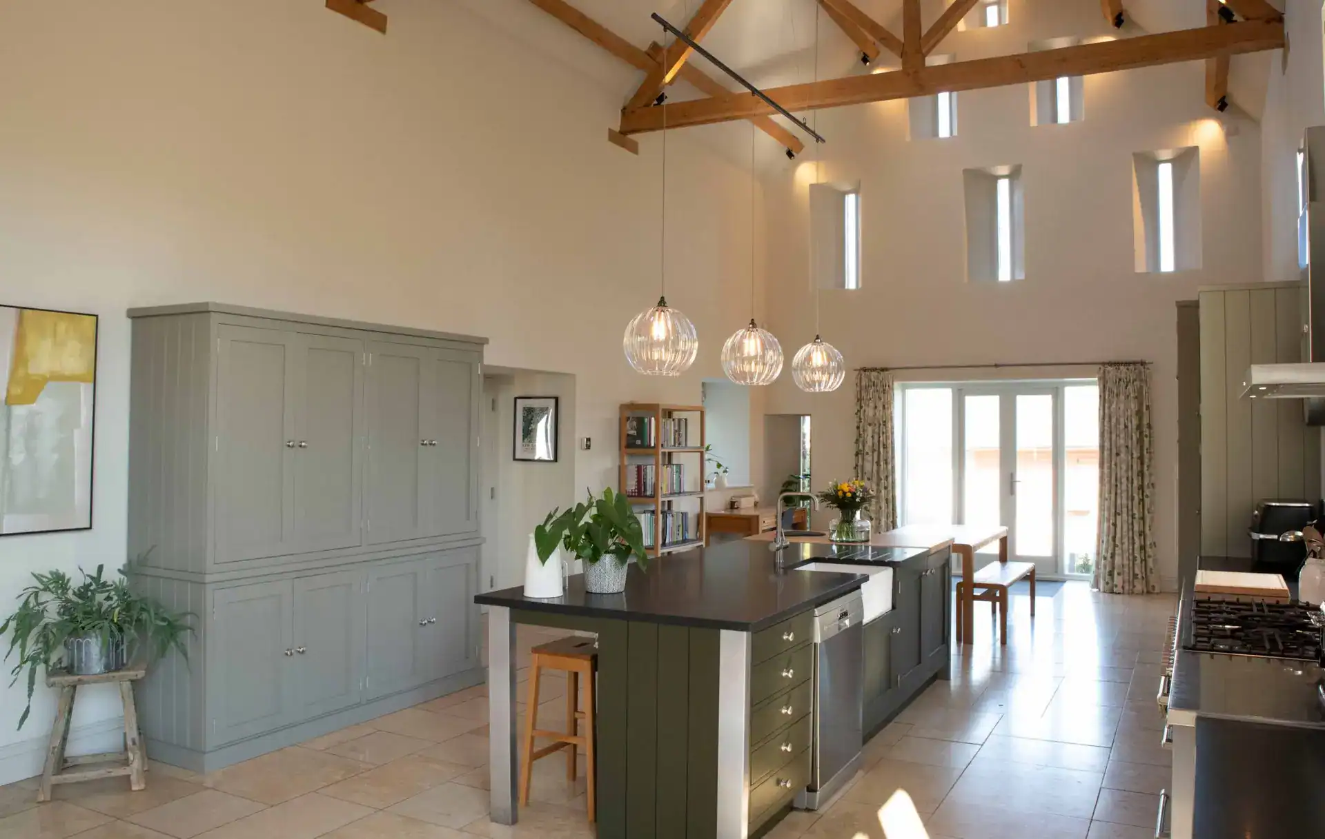Bright modern kitchen with wooden beams and pendant lighting, featuring a central island and large w.
