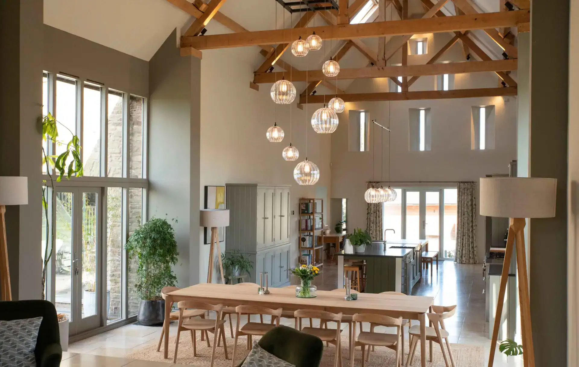 Elegant modern dining area with unique pendant lighting and wooden ceiling beams.