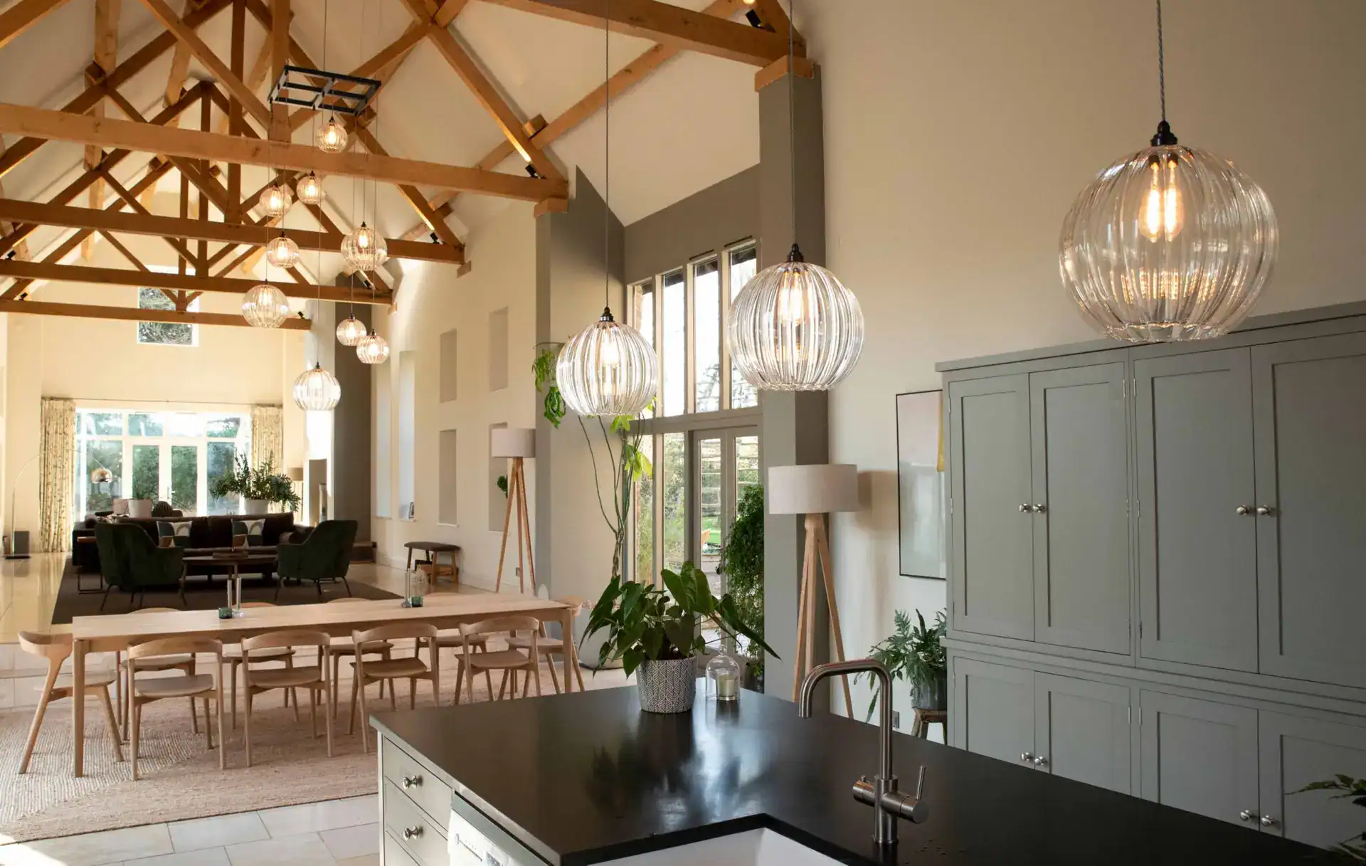 Modern kitchen and dining area with stylish lighting fixtures and wooden ceiling beams.