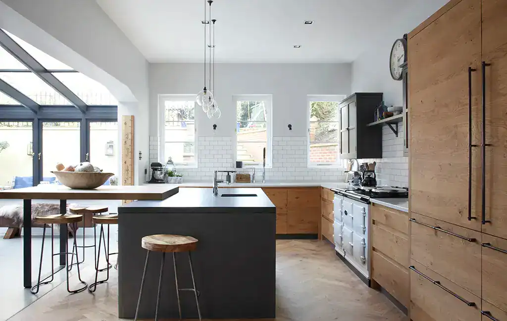 Bright contemporary kitchen featuring wooden cabinetry and a central black island with seating.