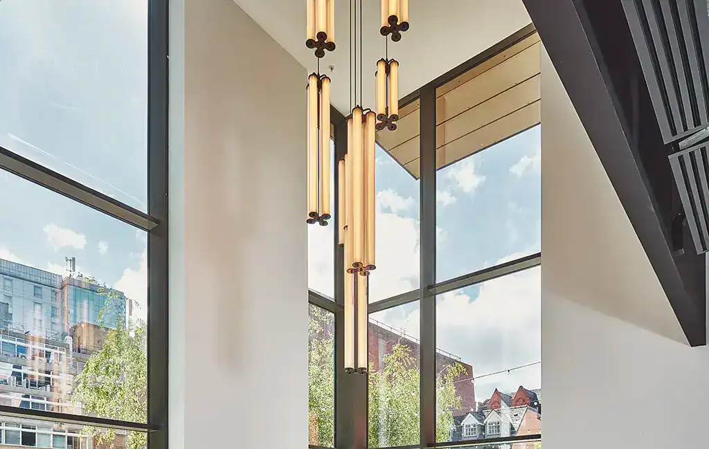 Elegant vertical pendant light fitting with multiple illuminated tubes.