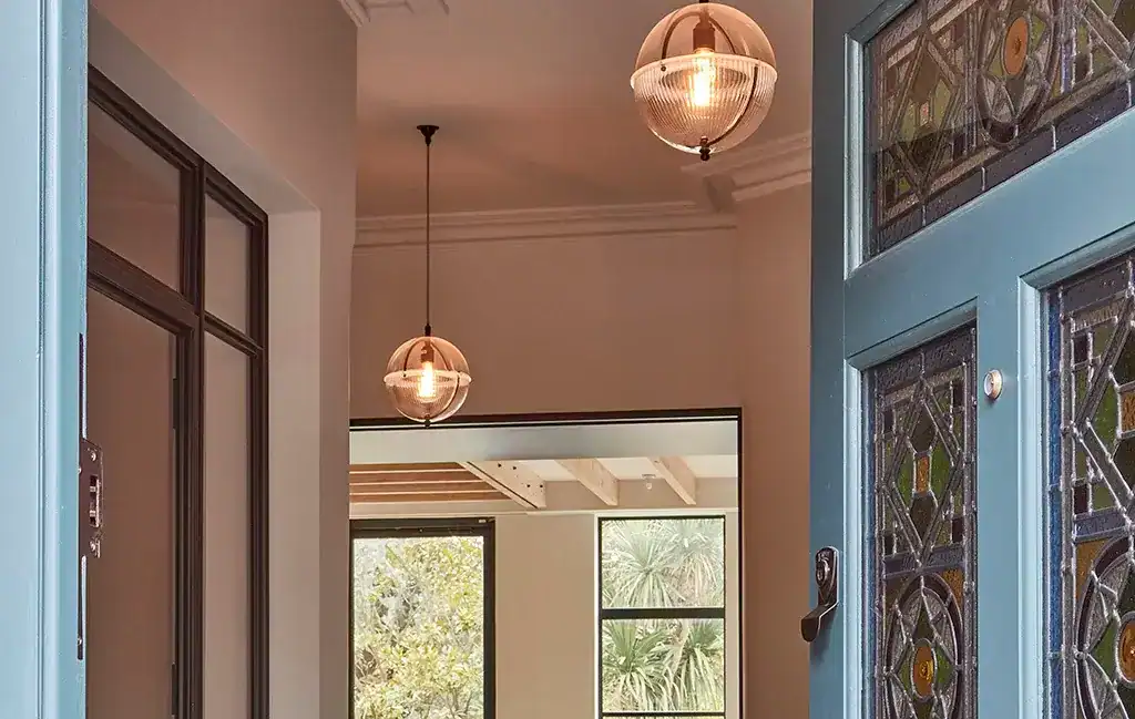 Entrance hall lighting with stylish pendant lights and decorative stained glass door. Bright and wel.