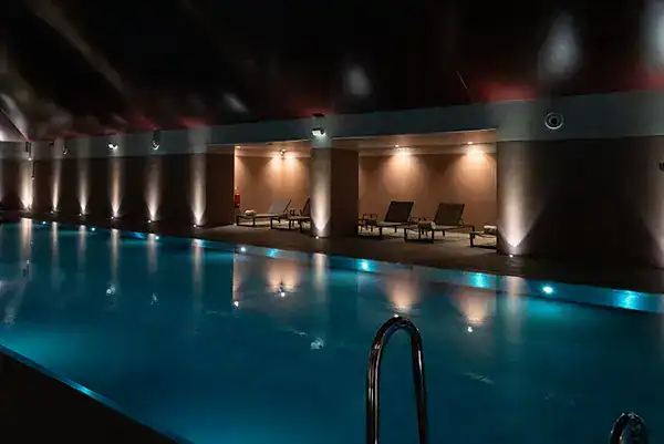 Pool area illuminated with modern lighting fixtures at Fritz Fryer UK.