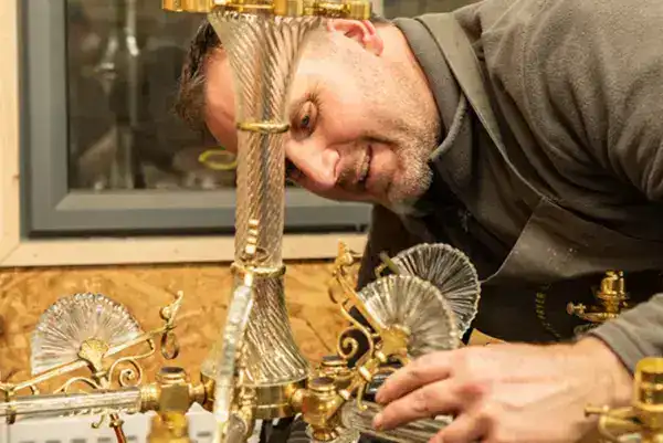 Expert craftsman working on ornate brass lighting fixtures.