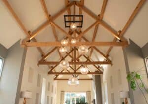 A modern barn conversion featuring a ribbed glass cluster suspended from the oak beams.