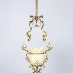 Antique pendant lantern with softly glowing vaseline glass and floral brass details.
