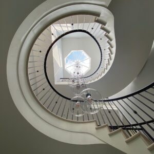 Spiral staircase with modern chandelier and skylight in a stylish interior.