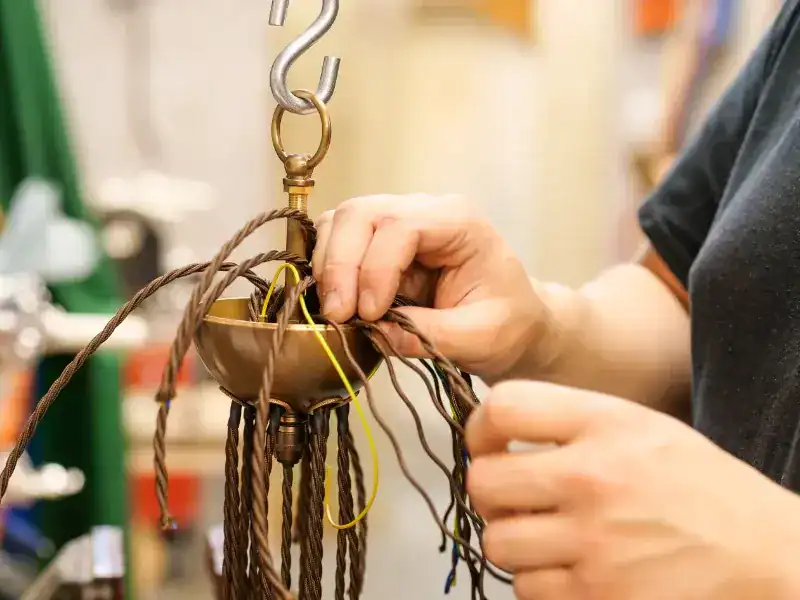 Handcrafting a decorative hanging light fixture at Fritz Fryer Lighting UK.