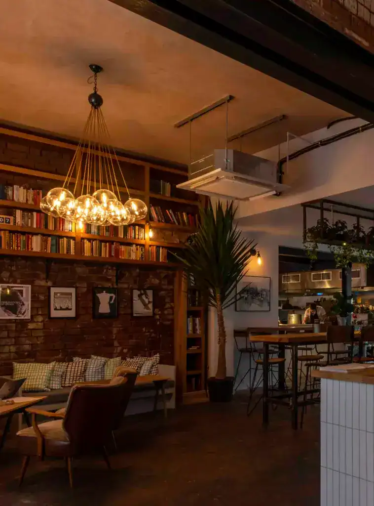 Warm industrial-style lighting fixture with multiple glass globes in a cosy cafe setting.