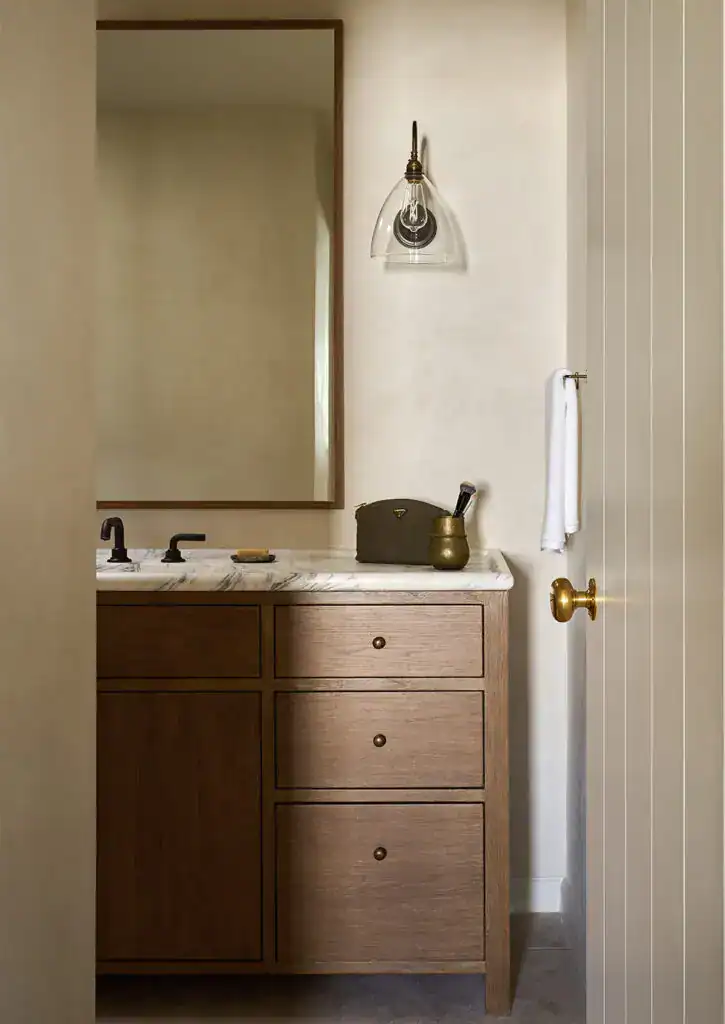 Bathroom vanity with wooden cabinet and wall-mounted light fixture.