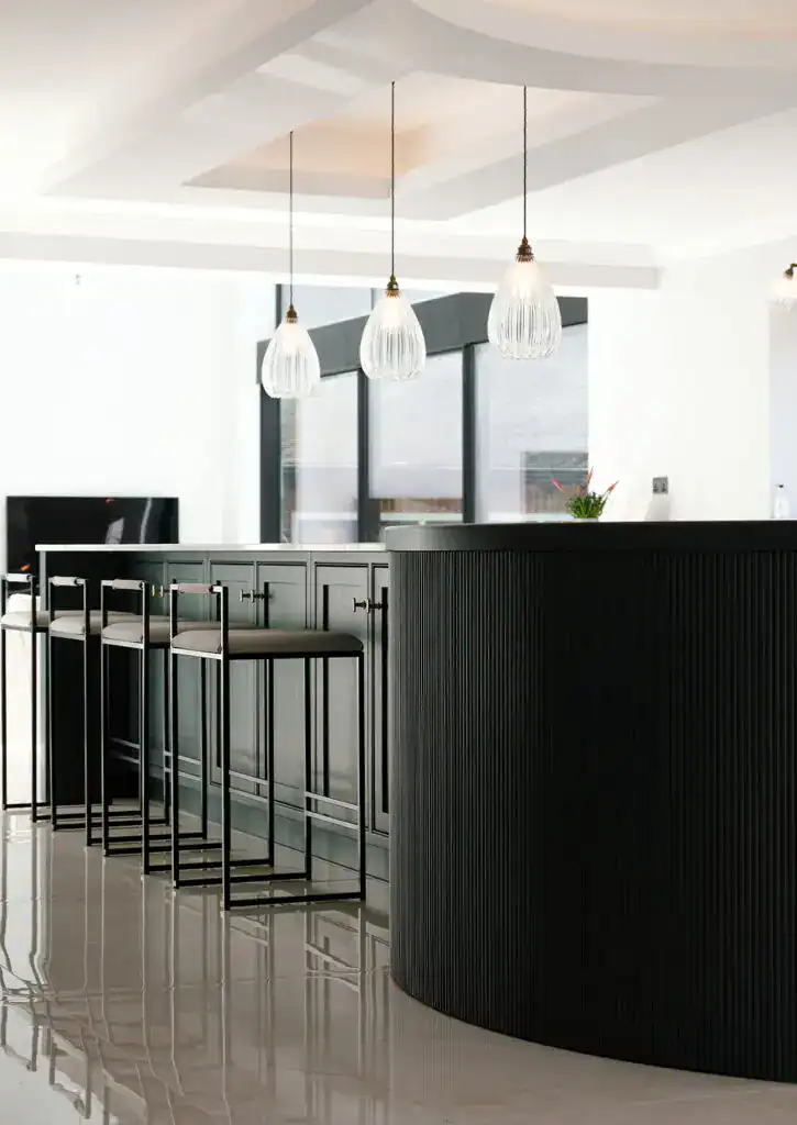 Pendant lights hanging above a stylish black bar counter in a modern interior.
