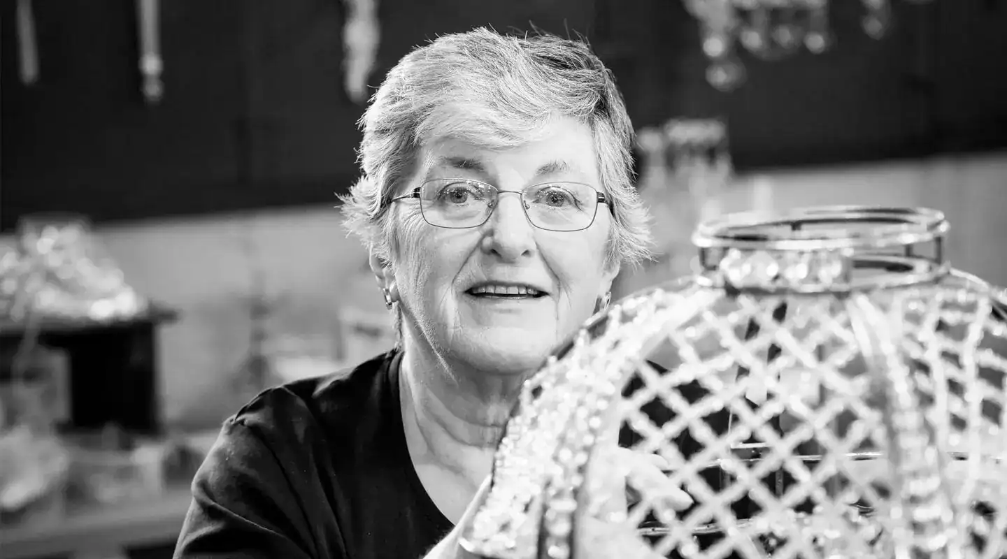 A woman working on a lighting fixture in a workshop.