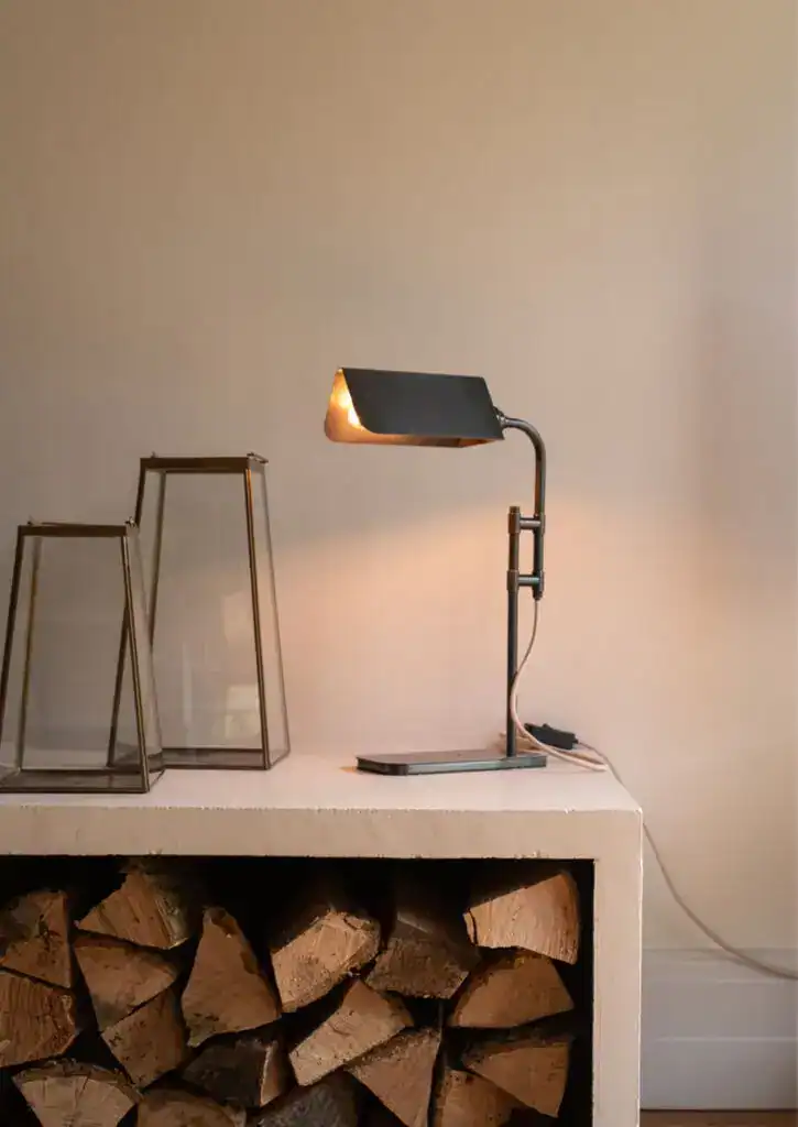 Contemporary black desk lamp on white surface with decorative glass lanterns in background.