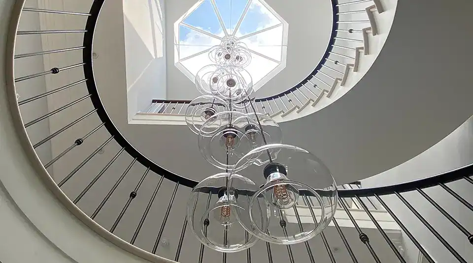 Elegant spiral staircase illuminated by contemporary pendant lights with glass globes.