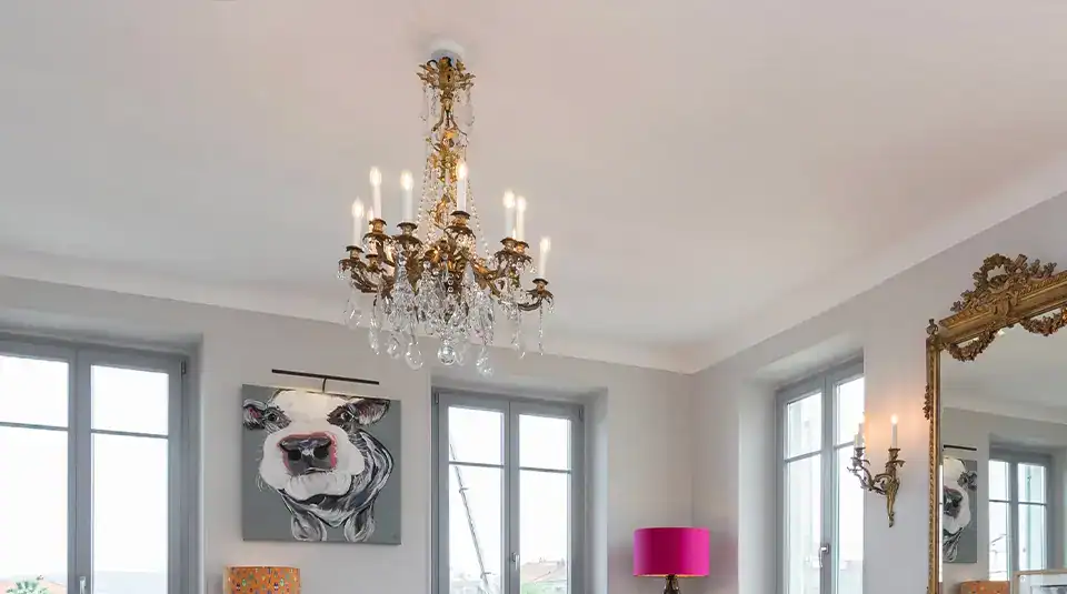 Crystal chandelier hanging from the ceiling with lit candles, illuminating a stylish living space.