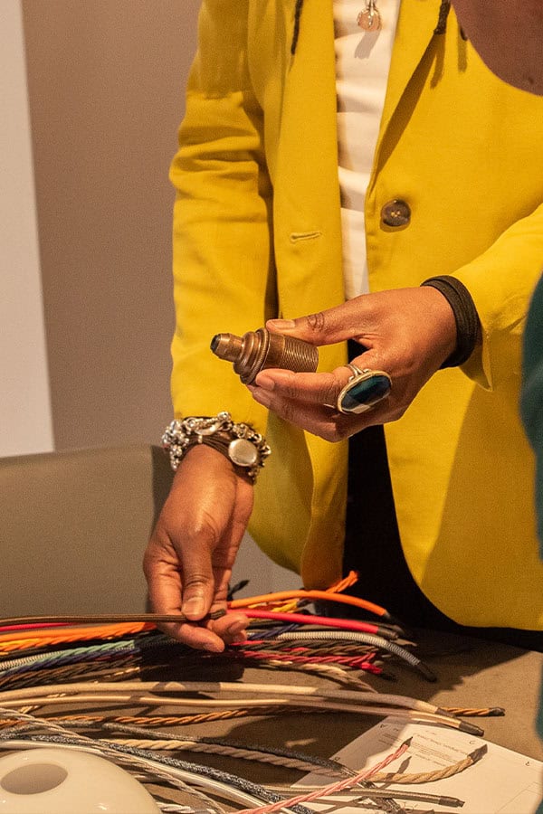 Person holding a vintage light fixture with electrical wires on table.