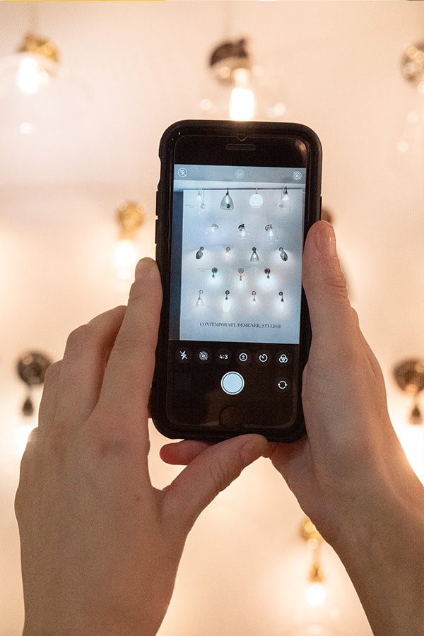 Person taking a photo of ceiling lights with a smartphone.