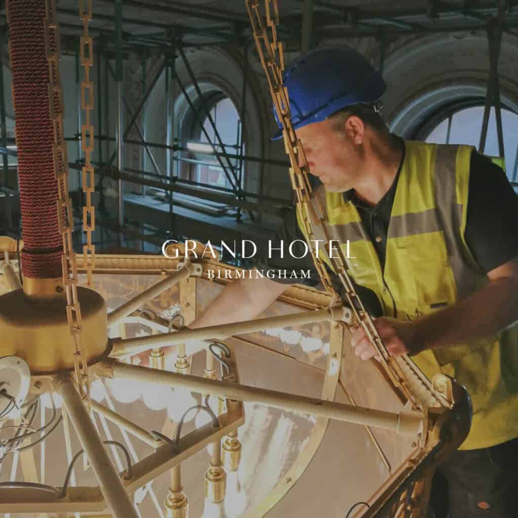 Engineer in high-visibility vest inspecting lighting and machinery at Grand Hotel Birmingham.